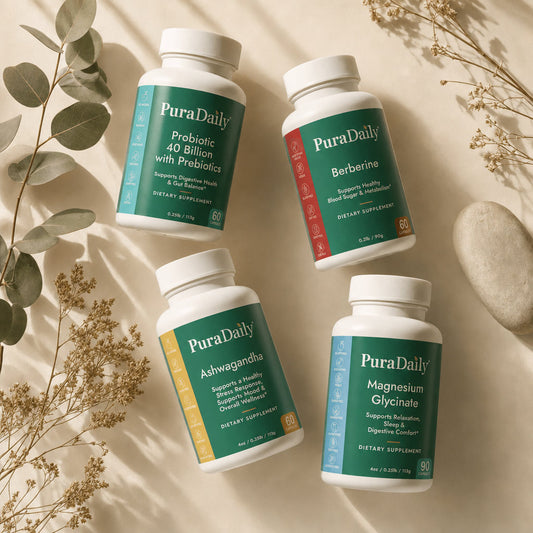 PuraDaily Complete Daily Wellness System four bottle flat lay with eucalyptus and dried botanicals